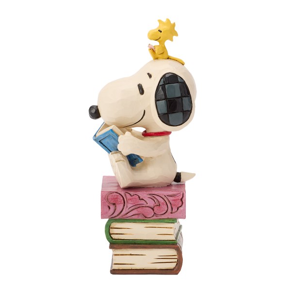 Snoopy leyendo libros apilados - Peanuts